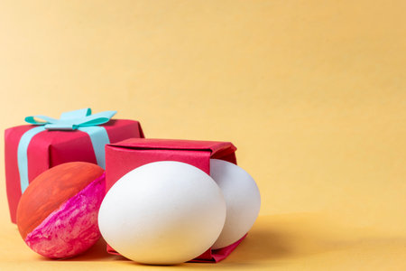 Colorful easter eggs in red gift box on yellow background. Copy space.の写真素材