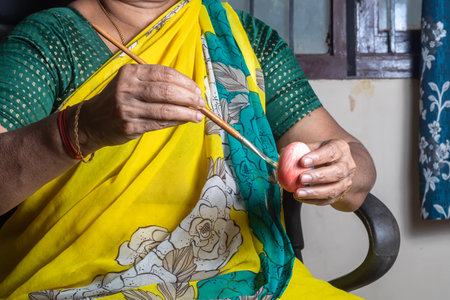 Indian woman holding an easter eggs in her hand and painting it with a paintbrush. Happy Easter.の写真素材