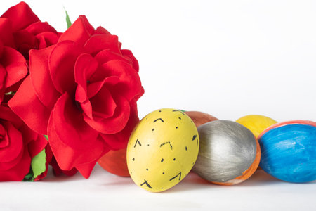 Easter eggs and red roses on a white background with copy space. Easter concept.の写真素材