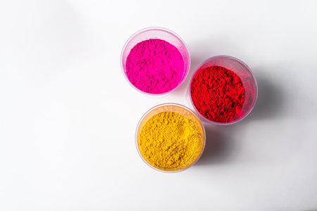 Colorful holi powder in plastic containers isolated on white background. Top view