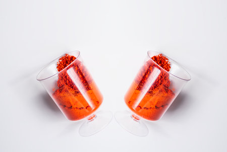 Two glasses of red holi powder on a white background, top view.の写真素材