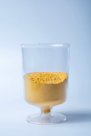 Colorful yellow holi powder sand in measuring cup on white background. Closeupの写真素材