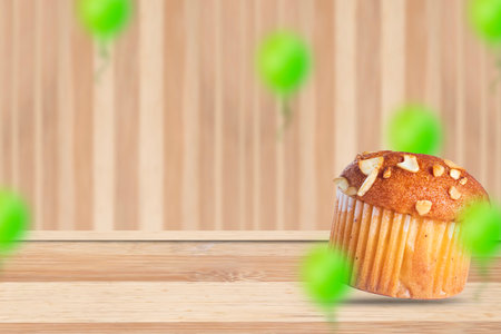 Almond muffin on wooden table with blurred green balloons.の写真素材