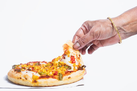 Indian woman's hand wearing gold bangle taking delicious vegetarian paneer pizza on white background. Closeupの写真素材