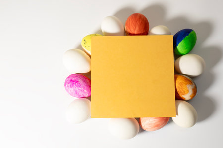 Colorful easter eggs with yellow card on a white background. Top viewの写真素材