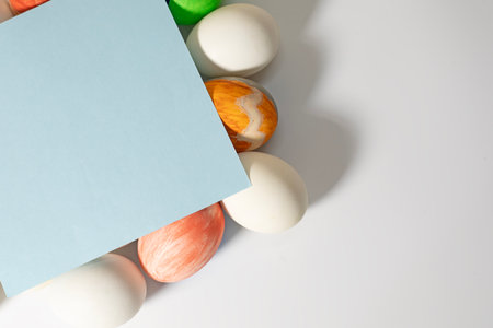Happy Easter concept. Easter eggs on a white background with a blue sheet of paper.の写真素材