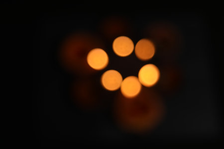 Defocused glowing clay lamps on black background. Bokeh effect. Top viewの写真素材