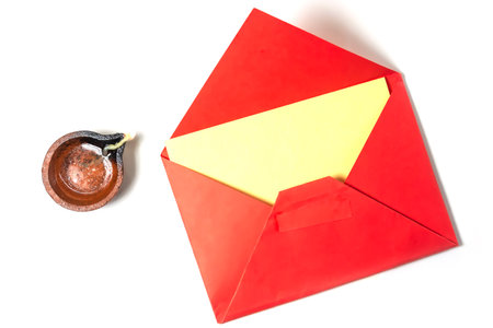 Vibrant red envelope with blank note for festive greetings beside it traditional burning clay oil...