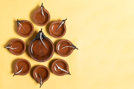 Hindu traditional clay diya arrangement for Diwali celebration on yellow background with copy space for text.の写真素材