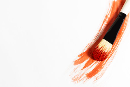 Red paint stroke on a white background with a brush to paint over it, top viewの写真素材