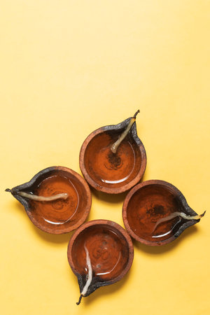 Happy Diwali - Traditional clay lamps arranged on yellow background during Diwali festival celebrations. Copy space for text.の写真素材