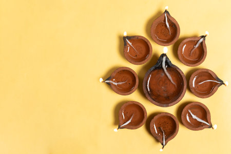 Hindu traditional clay diya arrangement for Diwali celebration on yellow background with copy space for text.の写真素材