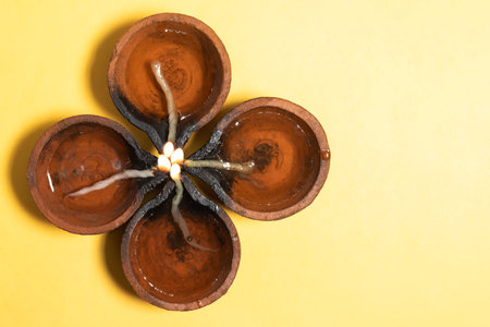Diwali Celebration: Diya oil lamps are arranged in a beautiful floral pattern on a vibrant yellow background during the Hindu festival celebration. Top viewの写真素材