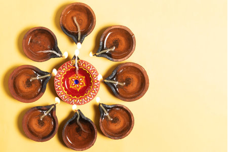 Happy Diwali - Traditional clay diya lamps arrangement on yellow background for festive celebrations.の写真素材