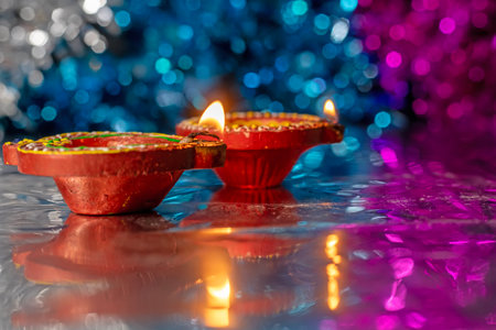 Two traditional Diwali diyas lit with colorful bokeh background. Celebration of Hindu Light Festival.の写真素材