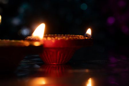 Traditional Diwali Diyas and beautiful light reflection with bokeh effect on dark background for...