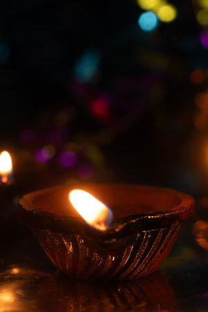 Traditional clay oil lamp lit with bokeh background. Selective focus.の写真素材
