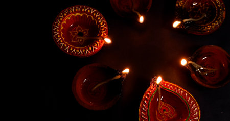 Traditional Diwali Diyas are arranged in a beautiful circle illuminated brightly on a dark background. Top viewの写真素材