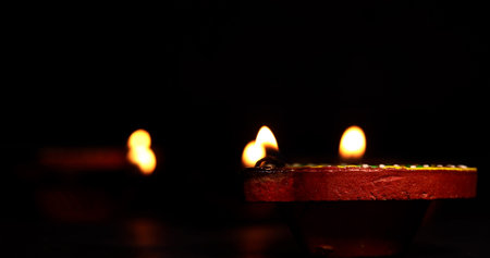 Illuminated Diwali diyas on the floor on dark background. Selective focus.