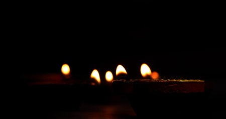 Glowing Diwali diyas on the ground in dark background. Selective focus.の写真素材
