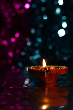 Glowing Diwali diyas with beautiful light reflection on the ground with bokeh effect in dark background. Selective focus.の写真素材