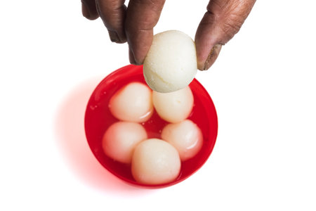 Closeup of Hand Holding Traditional Indian Sweet on White Backgroundの写真素材