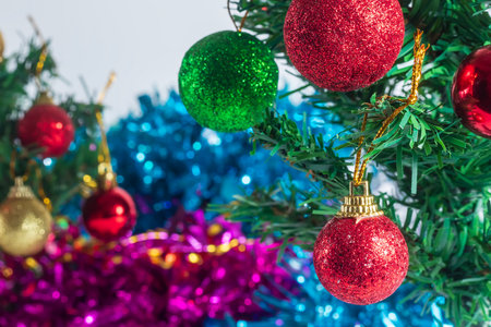A close-up shot of a beautifully decorated Christmas tree featuring vibrant red, green, and gold ornaments. The background is adorned with shimmering blue and pink tinsel, perfect for holiday themes and joyful celebrations.の写真素材