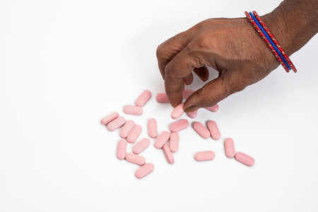 Top view of a female hand taking for a pink pill on a clear white background. healthcare concept