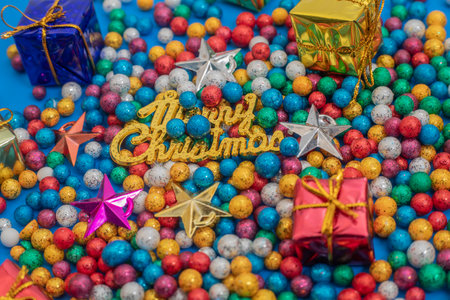 Vibrant Christmas decorations featuring colorful ornaments, glittering stars, and wrapped presents on a bright blue background, evoking festive joy and holiday celebration. A perfect display of holiday cheer and creativity.の写真素材