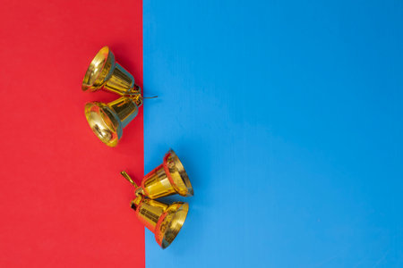A festive and vibrant scene featuring golden bells arranged on a bright red and blue background, symbolizing celebration and joy. Perfect for holiday themes, party decorations.の写真素材