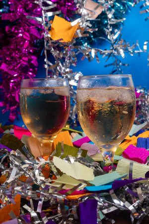 Two glasses of sparkling beverage surrounded by vibrant colored confetti and shiny streamers. Perfect for use in event promotions, social media content, and festive designs.の写真素材