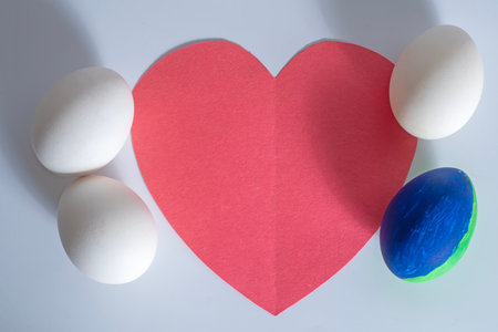 Top view of blue and white eggs placed against a bright red heart-shaped background.の写真素材