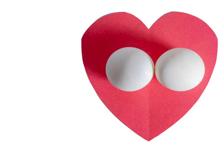 Top view of white eggs placed against a bright red heart-shaped background.の写真素材