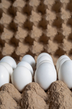 A close-up view of white eggs placed in a paper carton tray against a textured background.