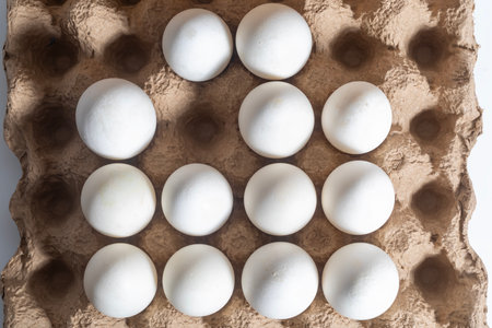 A carton holding twelve white eggs arranged in a grid pattern, viewed from above. Perfect for food, cooking, or egg related concepts.の写真素材