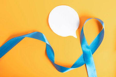 A blue awareness ribbon with a speech bubble on a vibrant yellow background represents causes and supportの写真素材