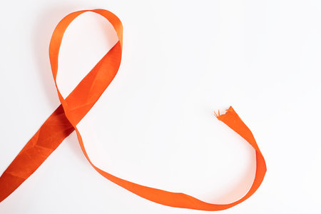 A bright orange ribbon is shown on a clean white background to represent awareness, support, and community based causesの写真素材