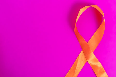 The orange awareness ribbon on a bright pink background symbolizes support, advocacy, and unity for causes such as awareness and campaigns.の写真素材