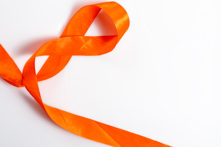 A vibrant orange ribbon beautifully arranged on a white surface symbolizing creativity, celebration and celebration. Perfect for designs.の写真素材