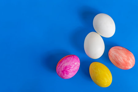 A top view of Easter eggs painted with white eggs on a bright blue background, conveying the festive spirit of Easter celebrations.の写真素材