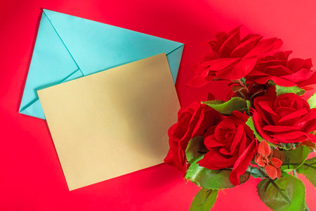 Bright red roses with a yellow greeting card on a red surface, expressing love and affection.の写真素材