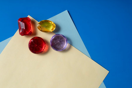 The top view of four gemstones in vibrant colors placed on a blue and yellow paper background shows beauty and elegance.の写真素材