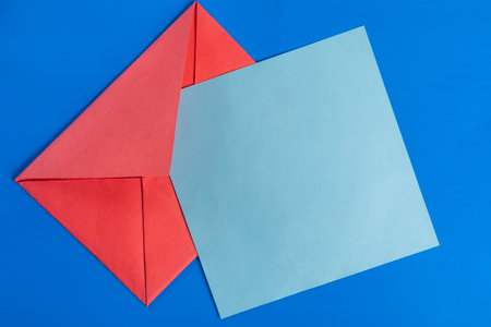 The red envelope paired with a blue card set against a vibrant blue surface shows simplicity and elegance in the design.の写真素材