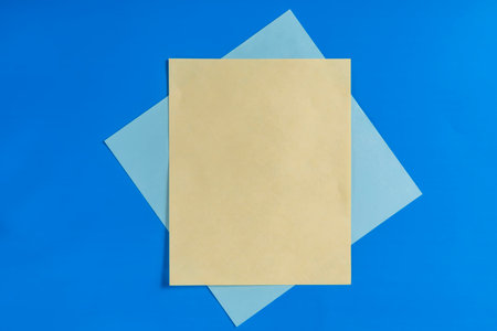 Yellow and blue sheets are creatively arranged on a bright blue background, creating a simple yet captivating composition suitable for design or conceptual use.の写真素材