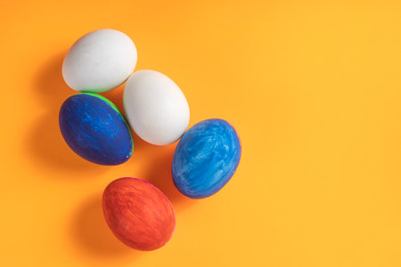Bright and colorful hand painted eggs are displayed on a vibrant orange surface, perfect for Easter and spring themes.の写真素材