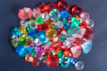 A blurred view of a variety of colorful gemstones scattered on a dark background creates a vibrant and shimmering pattern.の写真素材
