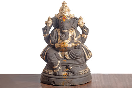 Clay Ganesha idol adorned with gold colored decoration on a white background. suitable for Ganesha...