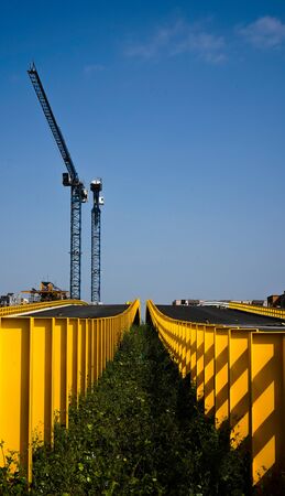 bridge under construction with cranes in blue skyの写真素材