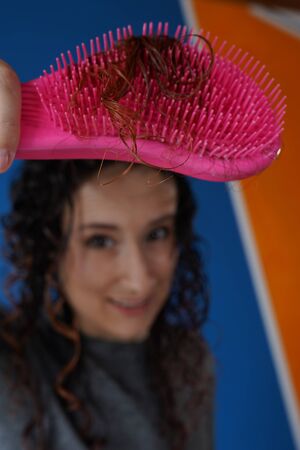 young woman in the background with a brush in her right hand and hair coming out of itの写真素材