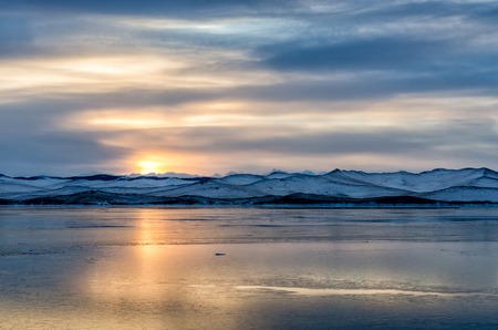 Beautiful orange sunset over the lake with mountainの写真素材